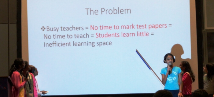 A school hackathon team talking about the problem they hope to solve, which is that teachers spend too long having to mark student test submissions